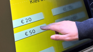 Vinger drukt op 50 Euro knop op scherm van Geldmaat automaat