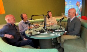 Ervaringsdeskundigen Rik en Erik aan een ronde tafel met opnameapperatuur in gesprek met interviewers Arlette en Gertjan van de podcast Nieuwe Knikkers.