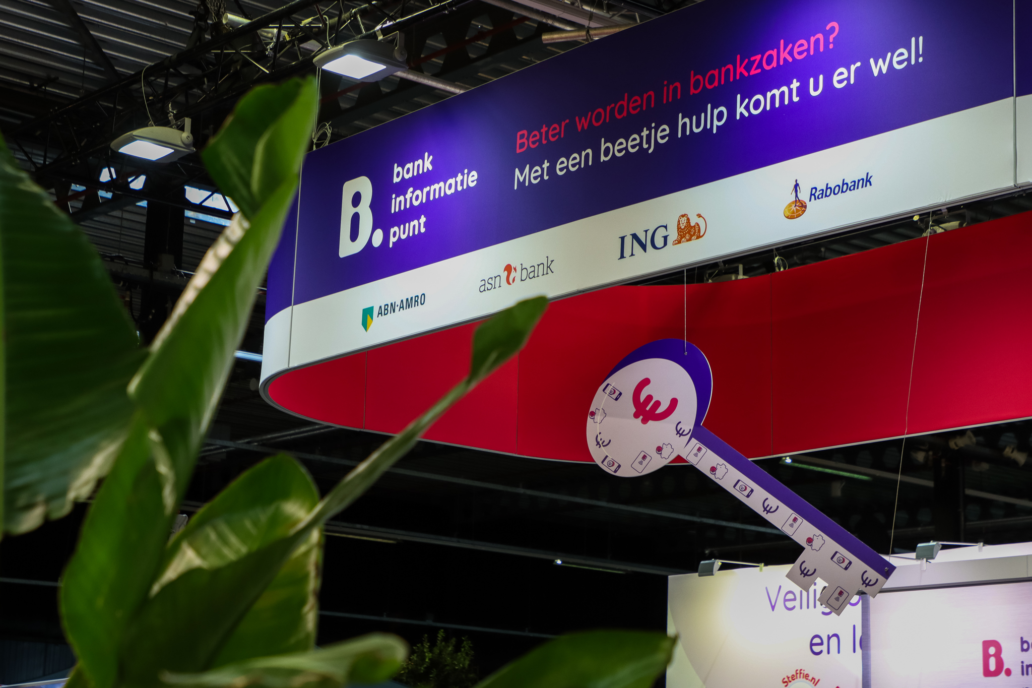 Folders en informatiefolders over digitale vaardigheden en betaalonderwerpen liggen klaar op een beursstand in een professionele ontmoetingsruimte.